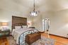 Bedroom featuring arched walkways, light wood-style floors, baseboards, high vaulted ceiling, and a chandelier