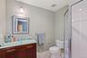 Full bath with toilet, vanity, a stall shower, and baseboards