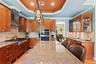Kitchen featuring stainless steel appliances, arched walkways, wall chimney range hood, light wood-type flooring, and light stone counters