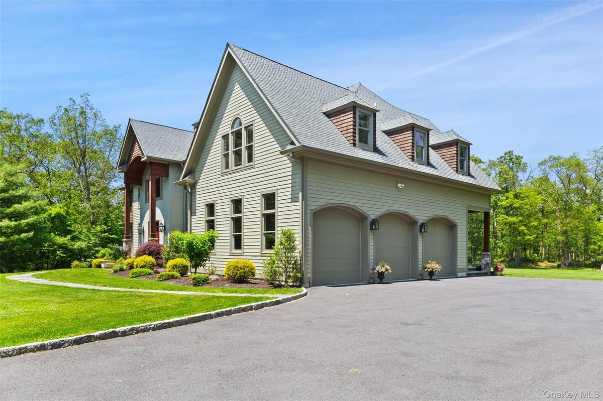 View of side of property with 3 car garage, large parking area and dormered roof