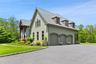 View of side of property with 3 car garage, large parking area and dormered roof