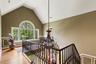Stairs with high vaulted ceiling, a chandelier, wood finished floors, and a wainscoted wall