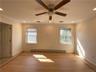 Empty room with a baseboard radiator, ceiling fan, light wood-type flooring, and crown molding