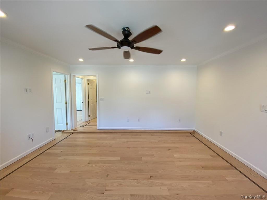 Empty room featuring light wood-type flooring, ceiling fan, and ornamental molding