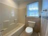 Bathroom featuring tile patterned flooring, tile walls, shower / bathing tub combination, and toilet