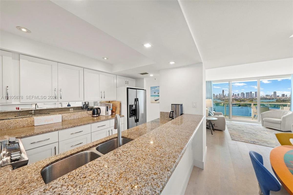 Kitchen featuring white shaker-style cabinetry, stone countertops, stainless steel dual-basin undermount sink, recessed lighting, and wood-finish floo