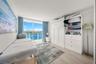 Floor-to-ceiling sliding glass door, custom built-in white cabinetry with integrated shelving and drawers, wood-finish flooring, and coastal skyline h