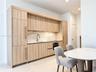 Modern kitchen featuring wood-finish cabinetry with integrated appliances, light-toned stone-style backsplash, undermount sink with a metallic pull-do