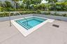 In-ground pool with integrated stepped entry and stainless steel handrail, bordered by stone-finish coping and tiered landscape planters with mature s