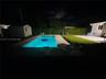 Backyard featuring an in-ground swimming pool, concrete patio, gravel area, perimeter hedging, and a detached storage structure