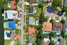 Aerial view of a waterfront residential neighborhood featuring in-ground swimming pools, mature palm trees, and canal access