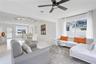 Open-concept interior featuring large-format tile flooring, matte black ceiling fan, and adjustable track lighting