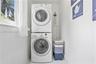 Dedicated laundry area featuring a white stackable front-load washer and dryer set and a window providing natural light