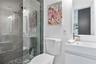 Bathroom featuring a frameless glass walk-in shower with horizontal tile surround and pebble tile flooring, white vanity with a rectangular integrated