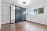 Room featuring wood-finish flooring, large multi-pane horizontal window, modern sputnik-style ceiling light, and full-height built-in wardrobe with mi
