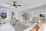 Open-concept interior featuring polished tile flooring, matte black ceiling fan, stainless steel refrigerator, and modern track lighting