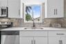 Kitchen featuring white shaker-style cabinetry, matte black hardware, stainless steel appliances, quartz countertops, and a metallic mosaic tile backs