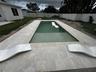 Rectangular in-ground pool with stone paver decking and perimeter vinyl fencing