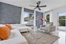 Living area featuring a floor-to-ceiling charcoal stone veneer accent wall, large picture windows, matte black ceiling fan with integrated lighting, a