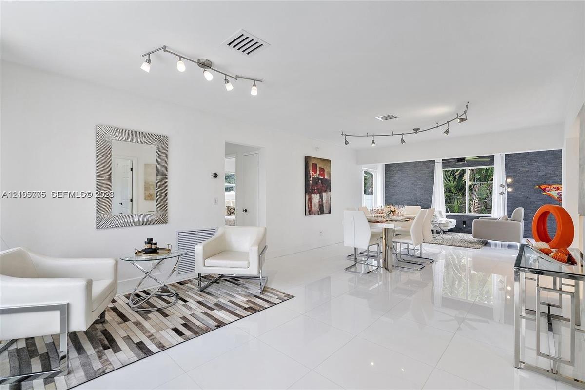 Open-concept interior featuring large-format white tile flooring, track lighting, and a textured charcoal accent wall