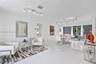 Open-concept interior featuring large-format white tile flooring, track lighting, and a textured charcoal accent wall