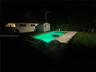 In-ground swimming pool with surrounding concrete patio, enclosed by vinyl privacy fencing and featuring a detached storage structure
