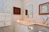 Custom vanity with integrated countertop and backsplash, undermount sink, dual-handle chrome faucet, and wall-mounted mirror