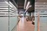 Glass doors with frosted horizontal detailing, wood-finish flooring, exposed industrial-style ceiling with ductwork, and linear overhead lighting