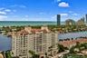 High-rise multi-story building featuring a red tile roof and arched architectural detailing, situated on a waterfront lot with canal access and coasta