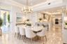 Open-concept dining and kitchen area featuring stone tile flooring, intricate ceiling millwork, recessed lighting, custom cabinetry, and a tiered cent