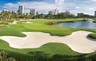 Expansive fairway featuring manicured grass, sand bunkers, a water hazard with wood bulkheading, and mature palm trees
