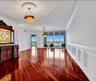 Polished wood-finish flooring, extensive wainscoting, ornate ceiling medallions, dual hanging light fixtures, and floor-to-ceiling glass sliding doors