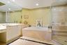 Bathroom featuring a built-in soaking tub, a frameless glass-enclosed shower with tile surround, white cabinetry, a large wall-mounted mirror, and til