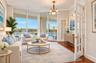 Living area featuring floor-to-ceiling glass sliding doors, polished wood-finish flooring, crown molding, a decorative ceiling medallion with a multi-