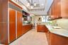 Kitchen featuring custom wood cabinetry, integrated full-height refrigerator, stone countertops, stainless steel undermount sink, and stone tile floor