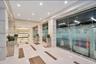 Polished stone flooring with inlaid wood-finish accents, large-format stone pillar cladding, glass-partitioned wall panels, recessed lighting, and a b