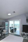 Sloped ceiling with recessed lighting and sliding glass doors opening to a waterfront balcony