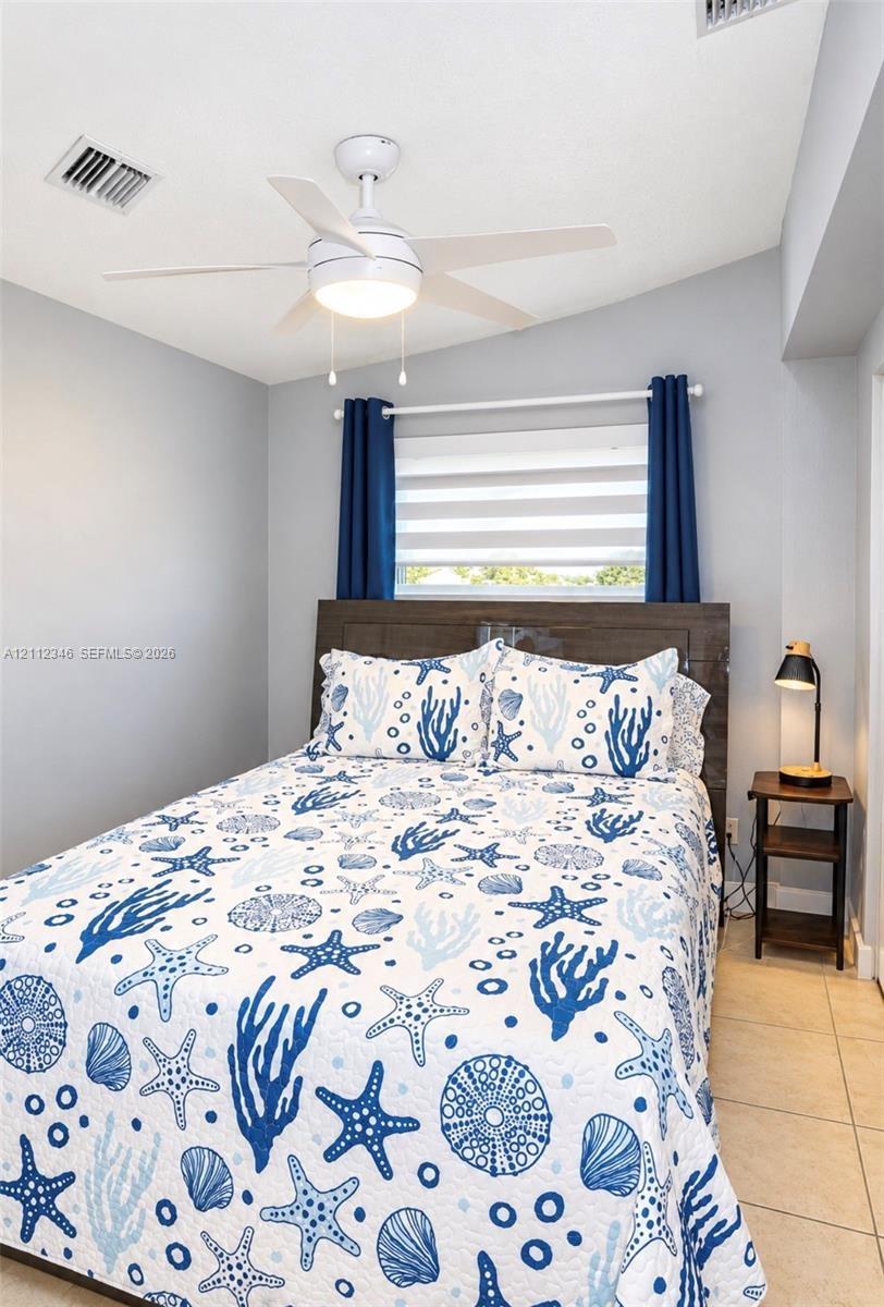 Ceiling-mounted fan with integrated light fixture, horizontal blind window treatment, and neutral tile flooring
