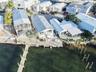 Waterfront property featuring a private boat dock, multi-level exterior decking, metal roof systems, and reinforced seawall