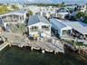 Waterfront residence featuring a metal roof, skylights, raised balcony with metal railings, and a concrete bulkhead with an attached private dock