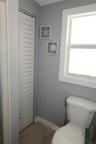 Full-height white louvered door, ceramic tile flooring, and a single-hung window with white casing