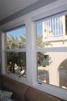 Dual white-framed double-hung windows with integrated roller shades and sand-finish exterior trim