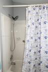 Bathtub and shower combination with a molded composite surround, integrated soap dish, chrome-finished multi-setting handheld shower head, and chrome 