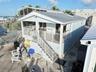 Waterfront property featuring a metal roof, elevated covered deck with white railing, exterior staircase, and siding