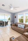 Sunroom featuring large ceramic tile flooring, vaulted ceilings, a central ceiling fan with integrated lighting, and glass sliding doors leading to a 
