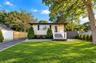 Exterior featuring horizontal siding, a raised white-railing entry deck, a paved driveway, and privacy fencing