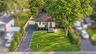 Single-story residence featuring a paved driveway, manicured lawn, stone-paver walkway, wood-fencing, and mature landscaping