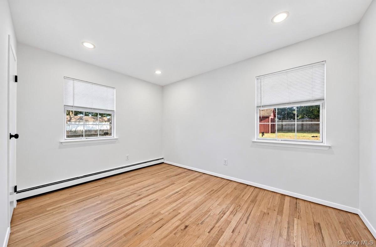 Interior room featuring wood-finish flooring, dual windows with blinds, and recessed lighting