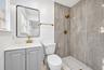 Bathroom featuring a grey vanity cabinet with a white countertop, brushed gold plumbing fixtures, a rectangular vanity mirror with a black frame, and 