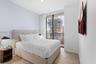 Floor-to-ceiling windows with access to a balcony, wood-finish flooring, and wall-mounted television hardware